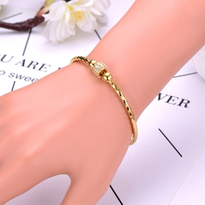 Detail of gold-tone beaded bracelet with sparkling pavé zircon bead on a wrist