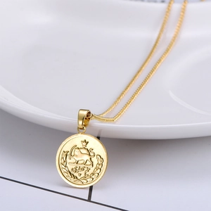 Vintage gold coin pendant necklace with embossed lion motif on a white ceramic plate