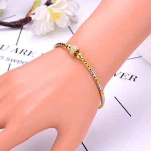 Detail of tricolor gold bangle with diamond-cut texture and zircon-studded spheres