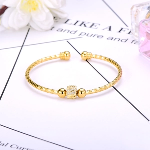 Detailed macro shot of a gold bangle with pave-set zircon beads and frosted texture