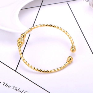 Macro detail of gold open bangle with micro-paved zircon bead and textured finish