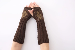 Detail van kabelgebreide patronen en ruitvormige jacquard op donkerbruine armwarmers