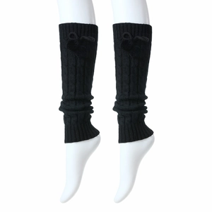 Detail of black cable-knit leg warmer with decorative bow and thick knitted texture