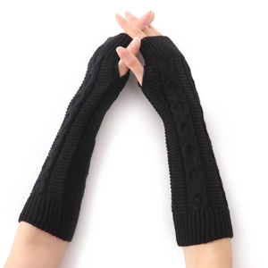 Détail de mitaines noires en maille torsadée montrant la texture et l'ouverture du pouce