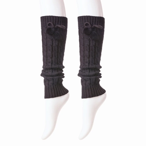 Detail of black cable knit leg warmer with decorative bow and elastic ribbed cuffs