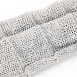 Macro shot of gray knitted wrist warmer showing thick ribbed texture and wool fiber detail