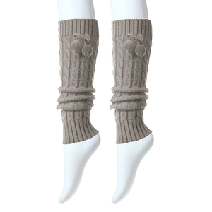 Detail of light brown cable knit leg warmers with fuzzy pom poms and ribbed texture