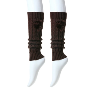 Close-up of thick cable knit leg warmers with plush pom-poms and bow tie details