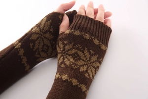 Dettaglio di guanti senza dita in maglia marrone scuro con motivi a fiocco di neve