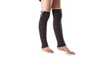 Detail of cable knit leg warmers with cream lace trim and decorative black buttons