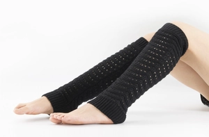 Detail of black knit leg warmers with delicate hollow-out wave pattern crochet textures