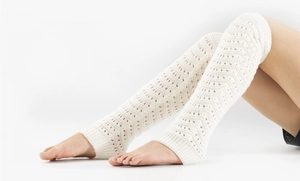 Detail of cream white knit leg warmers with hollow wavy pattern and elastic ribbed cuffs