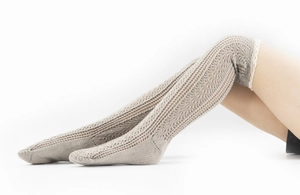 Detailed knit pattern of beige hollow out leg warmers with delicate white lace trim