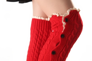 Close-up of red cable knit leg warmers with white lace trim and decorative black buttons