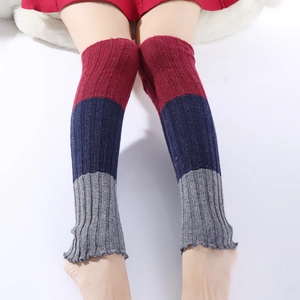 Detailed knit texture of three-color patchwork woolen leg warmers in red navy and grey