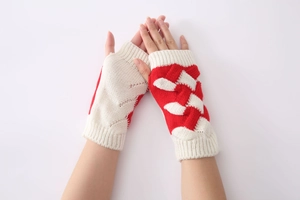 Close-up of red and white color-block knit fingerless gloves with cable stitch texture