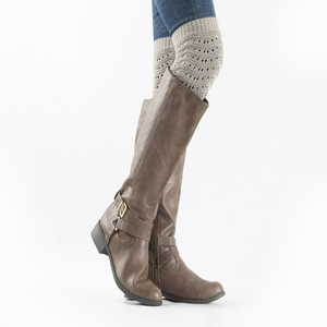 Close-up of knit hollow leg warmer styled with brown leather tall boots and buckle strap
