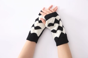 Close-up of black and white knit fingerless gloves with thick cable stitch pattern