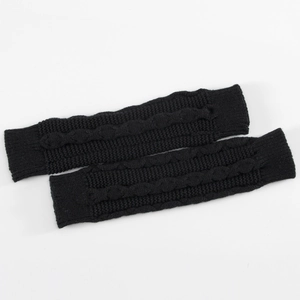 Gros plan sur des mitaines en tricot torsadé noir montrant la texture et les poignets
