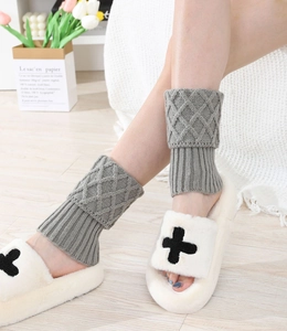 Detailed knit texture of grey cable-knit leg warmers paired with plush white slippers