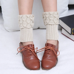 Close-up of beige knit leg warmers with diamond hollow pattern and striped texture