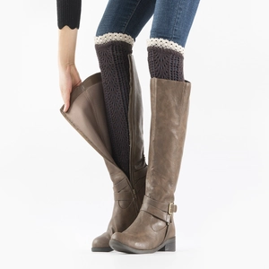 Detail of coffee knit leg warmers with cream lace trim worn with boots and denim