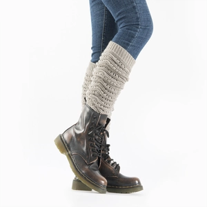 Detail of hollow wave pattern knit leg warmers in beige over denim jeans and boots
