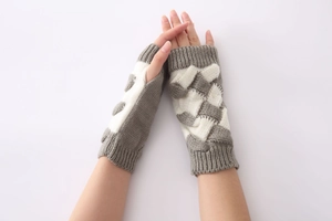 Detailed close-up of grey and white color-block cable knit fingerless gloves for autumn