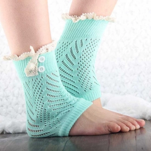 Dettaglio di scaldamuscoli verde menta con pizzo bianco e due bottoni laterali decorativi