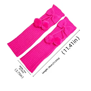 Detail view of pink knitted leg warmers with bow and pompom ornaments 29cm long