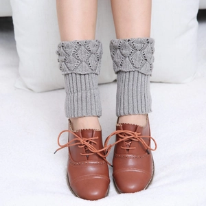 Detail of grey knitted leg warmers with scallop edges and diamond crochet patterns
