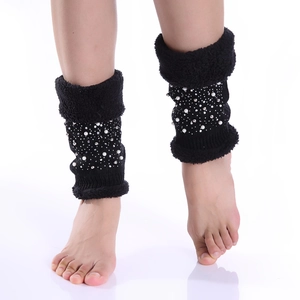 Close-up of black knitted leg warmers with white pearls and sparkling rhinestones