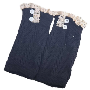 Dettaglio di scaldamuscoli neri in maglia con pizzo beige e due bottoni bianchi decorativi