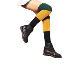 Detail of three-color knit leg warmers in green, yellow and black with high boots