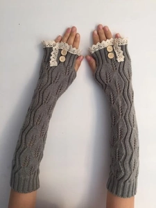 Détail de longs mitaines en maille torsadée grise avec dentelle et boutons en bois