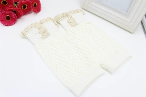 Dettaglio di scaldamuscoli in maglia crema con bordo in pizzo e due bottoni decorativi