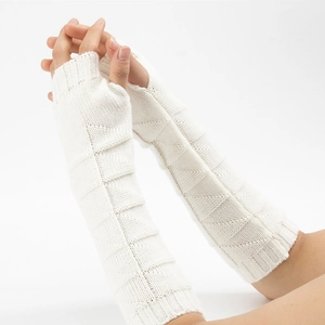 Close-up of white knit arm warmers with geometric triangle pattern and thumb hole