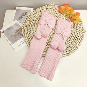 Detailed knit texture of pink leg warmers featuring cute bows and plush pompoms
