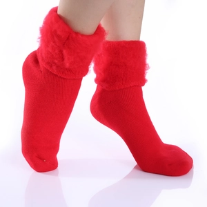 Detail view of red winter socks with plush faux fur trim and warm knitted texture