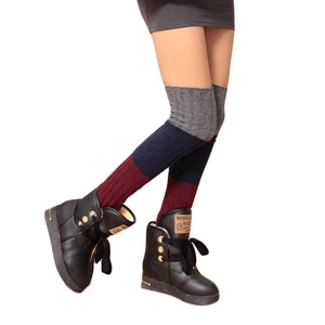 Detail of tricolor knit leg warmers in grey, navy and burgundy over black leather boots