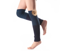Close-up of ribbed knit over-knee leg warmers with a fluffy pom-pom detail