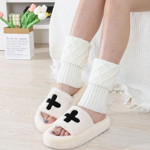 Detail of cable knit leg warmers paired with white plush cross slippers on light floor