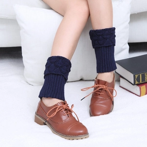 Macro view of dark blue cable knit leg warmers with ribbed cuffs and brown brogue shoes