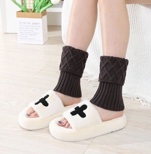 Detail of dark brown diamond patterned knit leg warmers with cream plush slippers