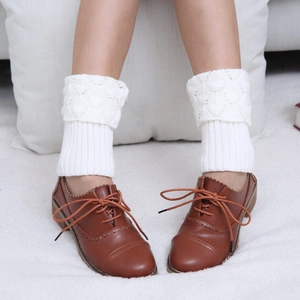 Detail of white knit leg warmers showing scallop edges and intricate pointelle patterns