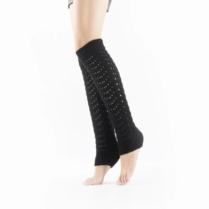 Close-up of black knit leg warmers featuring hollow crochet wave patterns and ribbed cuffs