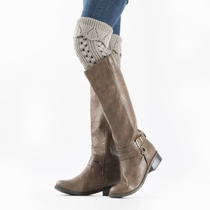 Detail of beige hollow knit leg warmers with brown leather boots and metal buckle accents