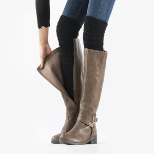 Detail view of black textured knit leg warmers worn inside tall brown leather boots