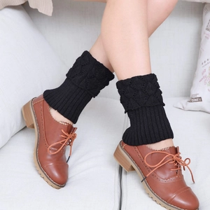 Detail of black cable-knit leg warmers paired with brown leather oxford shoes