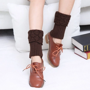 Detailed view of dark brown knitted leg warmers with diamond hollow patterns